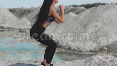 穿着黑色运动服的运动型黑发女孩在一个白色粉笔采石场和蓝色的水对抗。<strong>蹲下</strong>