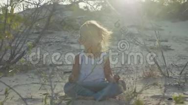 小女孩在<strong>沙漠里</strong>冥想。 日落时坐在沙滩上<strong>的</strong>孩子温暖。