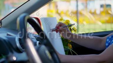 艺术家，美丽的黑发女人，坐在车里，画<strong>铅笔素描</strong>，画一束黄色的蒲公英。 由