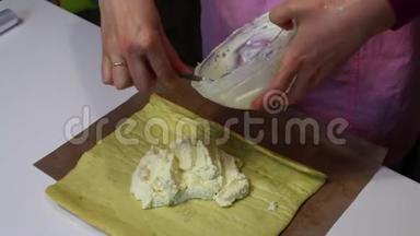 一个女人正在海绵蛋糕上撒奶油。 饼干卷的准备.. 准备阶段。