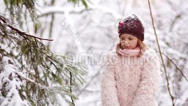 一个甜美的女孩从冬天的树枝上摇雪。 冬季运动会，节日快乐，圣诞节假期