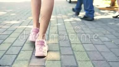 特写镜头。 女腿穿着时尚的粉红色运动鞋。 带着人行道走在街上的女孩。 自然阳光充足