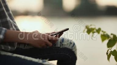 在市中心日落时分，女孩正坐在智能手机上输入一条信息。