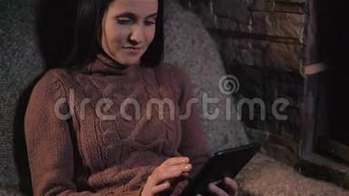 使用数码平板电脑在家中壁炉旁的年轻女子，近距离拍摄