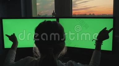 金发少女坐在粉红色日落背景下的绿色大屏幕显示器前的虚拟现实眼镜中