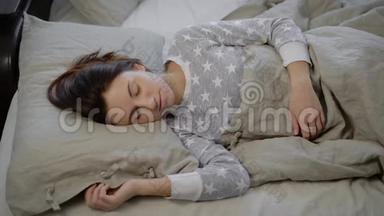 在床上的女孩。 那个年轻的黑发女人下午睡觉。 穿着灰色睡衣带<strong>星号</strong>的女人。 一个黑发女人