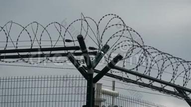 带刺铁丝网的安全围栏，灰色的天空。 带刺铁丝网的栅栏。