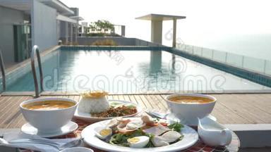 泰式菜肴。 4k. 池边的桌子。 泰国传统午餐在游泳池旁，改变焦点