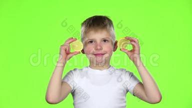 带着<strong>柠檬片</strong>的孩子舔它们，露出鬼脸。 绿色屏幕。 慢动作