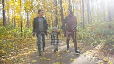 一家人和一个小女儿在秋天公园散步