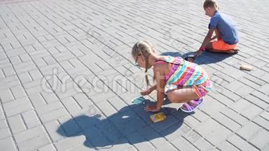 孩子们，一个男孩和一个女孩戴着太阳镜，用彩色蜡笔在沥青上画画，街道瓷砖。 炎炎夏日..