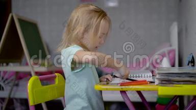 小女孩坐在桌子旁用铅笔画画。小孩正在学画画