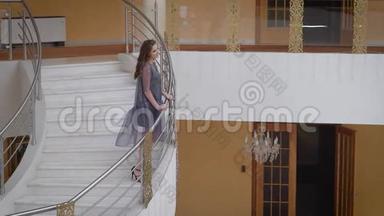 智能大厅的门厅。 巨大的梯子，大理石地板，漂亮的吊灯.. 女孩模特在梯子上摆姿势。 公平