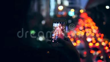 年轻的Hipster<strong>旅游</strong>女孩采取智能手机图片在夜间<strong>曼谷</strong>城市汽车交通，<strong>泰国</strong>。 4K.