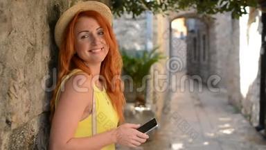 红发女游客在古城街道上使用智能手机