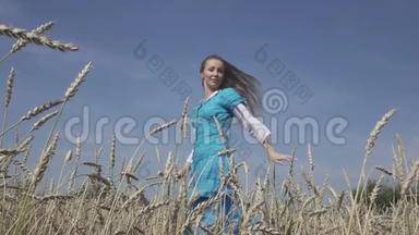 快乐的年轻苗条的女人，穿着蓝色连衣裙的长发，在夏天阳光明媚的日子里，在成熟的<strong>麦子</strong>里旋转。 慢动作