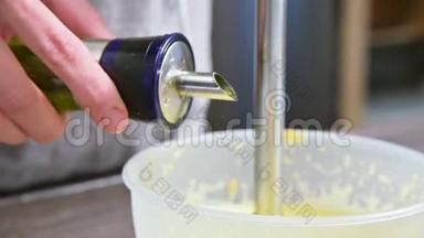在塑料碗里用<strong>搅拌</strong>器将自制蛋黄酱的混合物<strong>搅拌</strong>。 橄榄油