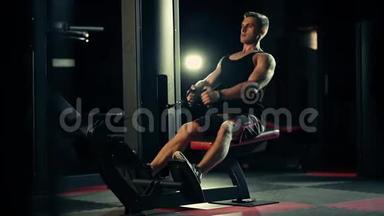 肌肉发达的人在黑暗的健身房锻炼背部肌肉，举重
