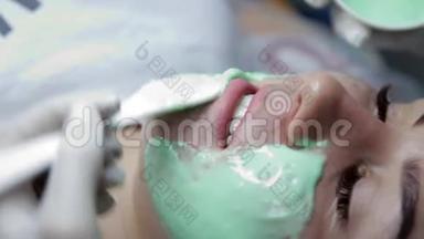 美容师用海藻酸钠面膜敷在病人的脸上后进行生物消毒