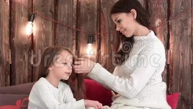 快乐的母亲在她唱圣诞歌时`女儿梳头