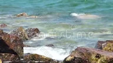海浪溅到多石的海滩上。波涛拍打岩石海滩。蓝色海水和大石头背景。