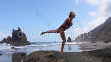 一条腿站在石头上做瑜伽平衡的女孩。 心灵的平静。 健康的生活方式。 平衡与和谐