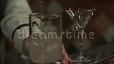酒保在玻璃杯里加马提尼摇冰块，然后倒入空玻璃杯