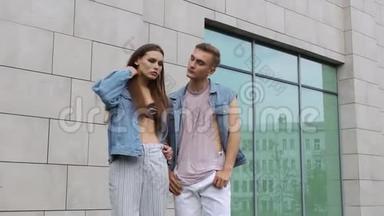 男人和女人穿着休闲的街头服装，摆在灰色的墙前