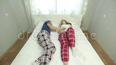 年轻的男人和<strong>孕妇</strong>穿着<strong>睡衣</strong>躺在卧室的床上。
