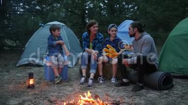 妈妈、爸爸和儿子在森林里休息，妈妈、孩子和爸爸围着火烤玉米，<strong>全家</strong>晚上野餐