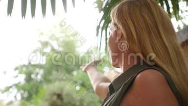 夏天下雨时，一个女人站在棕榈树下。 4k，慢镜头