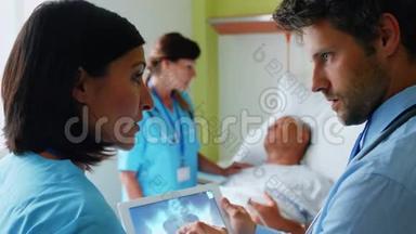 医生讨论数字平板电脑上的x光，护士在后台与病人互动