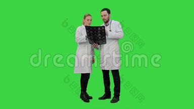 医生检查X射线，并讨论在绿色屏幕上手术的成功结果，Chroma键。