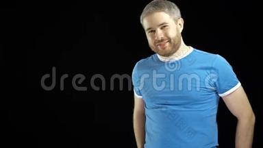 身穿蓝色t恤、长胡子的帅哥在黑色背景下对着镜头微笑。 4K视频
