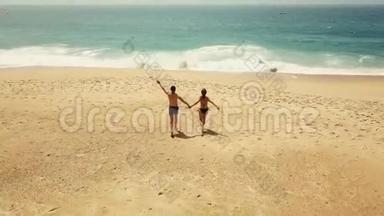 幸福的夫妇无忧无虑地跑到海滩上的水上。 葡萄牙美丽的海洋海岸