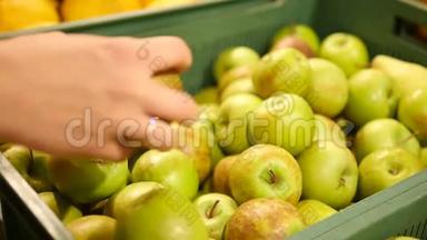 超市里的女孩选择绿色苹果。 女手在超市选购青苹果.. 一大堆