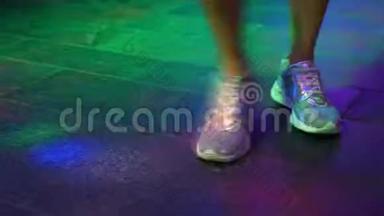 穿着银色鞋子`女人的腿在迪斯科酒吧的舞池里跳舞。 来自萨菲托夫的光。 4k