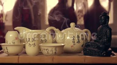 香气和啜饮杯，茶壶和佛像上的木制茶板茶班。 烧香的熏烟
