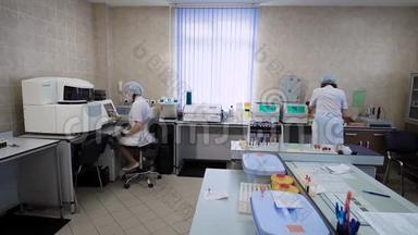 妇女实验室的技术人员穿着白大褂在一<strong>家私</strong>人诊所对病人进行分析，他们检查血液