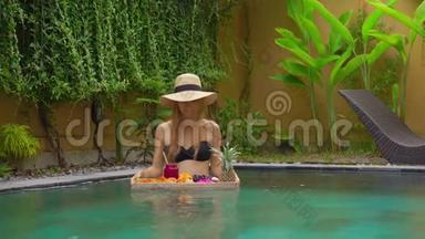一位年轻的女游客在<strong>私</strong>人游泳池的一张漂浮的桌子上有自己的<strong>私</strong>人早餐。 热带海滩