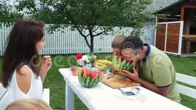 夏天，在花园里，爸爸和一个四岁的儿子切了一个西瓜，吃了它，玩得开心，一个男孩喜欢西瓜