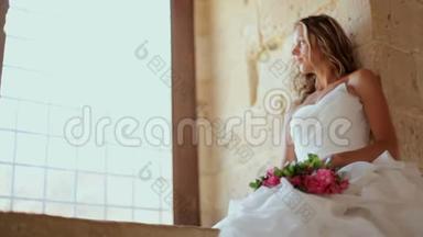 一位美丽的新娘坐在老城堡的窗户附近