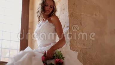 一位美丽的新娘坐在老城堡的窗户附近
