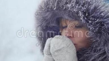 一个穿着手套的好女孩在冬天的公园里喝热茶取暖。