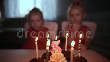 两个<strong>可爱</strong>又穿衣服的小<strong>双胞胎</strong>姐妹聚集在节日蛋糕附近，点燃蜡烛。 在家里过生日。