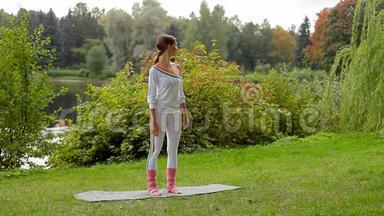 年轻女子站在河岸的<strong>防滑</strong>垫上做瑜伽运动