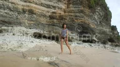 年轻的n<strong>款黑色</strong>泳衣和条纹衬衫正沿着巴厘岛海湾的沙滩漫步，望着大海