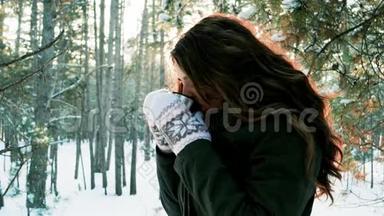 冬天在户外喝茶的漂亮女孩可爱的女孩拿着一个杯子，从中冒出蒸汽，年轻的女人喝茶