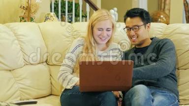 朋友-年轻的韩国男人和高加索女人在家休息。 好好享受笔记本电脑吧