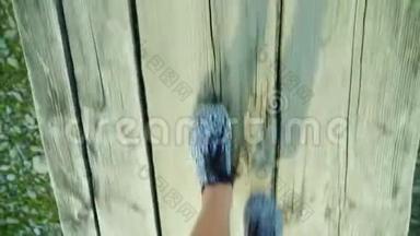 视频：一个女人的脚正沿着一座狭窄的木桥走过一条山河。 危险和冒险